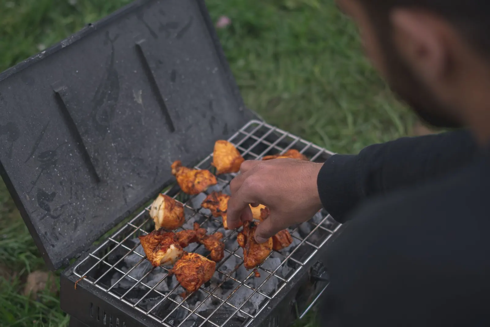 The chef at the mangal, laying marinated chicken over live charcoal